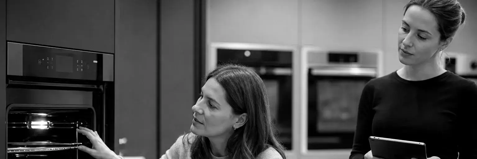 A consumer examining a built-in oven while a Stratega moderator records her responses during a central location test in Poland